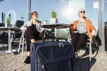 Businesswomen sitting on chairs with luggage — Stock Photo