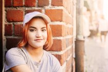 Young woman sitting by brick wall — Stock Photo