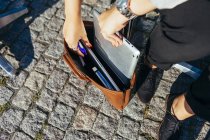 Mujer poniendo tableta digital en el bolso - foto de stock