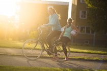 Women on bicycle with soccer ball — Stock Photo