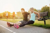Girl and boy doing exercise on bench — Stock Photo