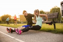 Girl and boy doing exercise on bench — Stock Photo