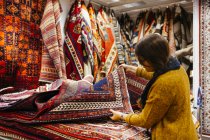 Jeune femme faisant du shopping pour les tapis — Photo de stock