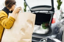 Frau lädt Einkaufstasche in Kofferraum — Stockfoto