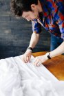 Male designer pinning white textile — Stock Photo