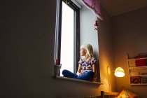 Mädchen schaut durch Fenster — Stockfoto