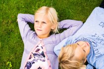 Дівчина з братом лежить на траві — стокове фото