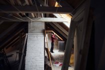 Man working in attic under construction — Stock Photo