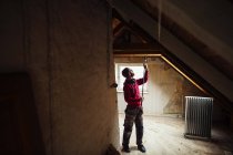 Mann mit Arbeitsgerät renoviert Dachboden — Stockfoto