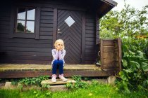 Chica triste sentada en el porche - foto de stock