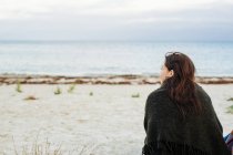 Femme assise sur la plage — Photo de stock
