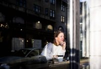 Улыбающаяся женщина смотрит в окно — стоковое фото