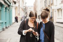 Жінки друзі використовують смартфон — стокове фото