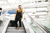 Donna d'affari con bagagli sulla scala mobile — Foto stock