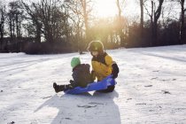 Boy with brother playing with sled — Stock Photo