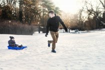 Young father tobogganing baby boy — Stock Photo