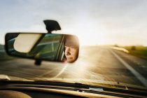 Reflection of woman in rear-view mirror — Stock Photo
