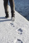 Woman walking on snow covered footpath — Stock Photo