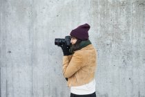Woman photographing against wall — Stock Photo