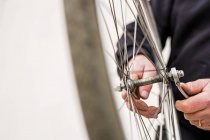 Homem sênior apertando pneu de bicicleta — Fotografia de Stock