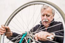 Старший человек затягивает велосипедную шину — стоковое фото