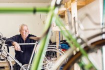 Старший ремонтник спирається на велосипед — стокове фото