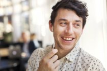 Hombre sonriendo mientras habla a través de auriculares - foto de stock
