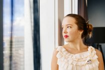 Thoughtful woman standing by window — Stock Photo