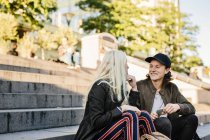 Happy friends sitting on steps — Stock Photo