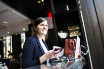 Empresária com smartphone e laptop no café — Fotografia de Stock