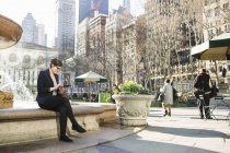 Бізнес-леді, використовуючи планшет, сидячи проти фонтану — стокове фото