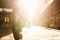 Businessman with briefcase walking on city street — Stock Photo