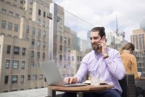 Businessman talking on phone while using laptop — Stock Photo