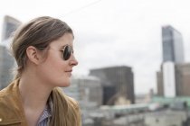 Businesswoman wearing sunglasses standing against buildings — Stock Photo