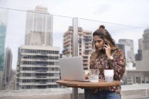 Woman using laptop at rooftop restaurant — Stock Photo