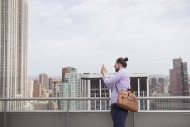 Человек фотографирует город, стоя на крыше — стоковое фото