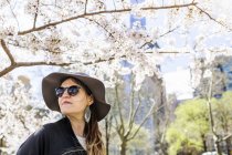 Frau schaut weg gegen blühenden Baum — Stockfoto