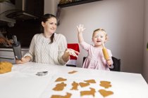 Madre e hija disfrutando mientras hacen galletas - foto de stock