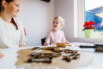 Daughter talking to mother while preparing cookies — Stock Photo
