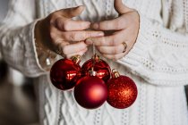 Женщина держит красные рождественские безделушки — стоковое фото