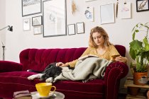 Frau liest Buch auf Sofa — Stockfoto