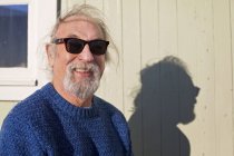 Hombre con gafas de sol de pie contra la cabaña de la playa - foto de stock