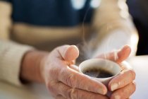 Homem segurando xícara de café na mesa — Fotografia de Stock