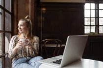 Усміхнена жінка сидить у кафе — стокове фото