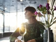 Frau mit Weinglas sitzt am Tisch — Stockfoto