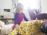 Nettes Mädchen packt Geschenk zu Hause aus — Stockfoto