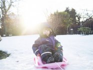 Happy girl sledding on snow — Stock Photo