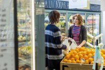 Женщина и мужчина разговаривают во время покупки апельсинов — стоковое фото