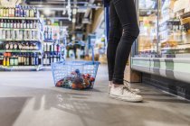 Young woman standing by shopping basket — Stock Photo