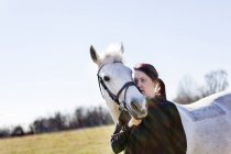 Donna che abbraccia cavallo sul campo — Foto stock